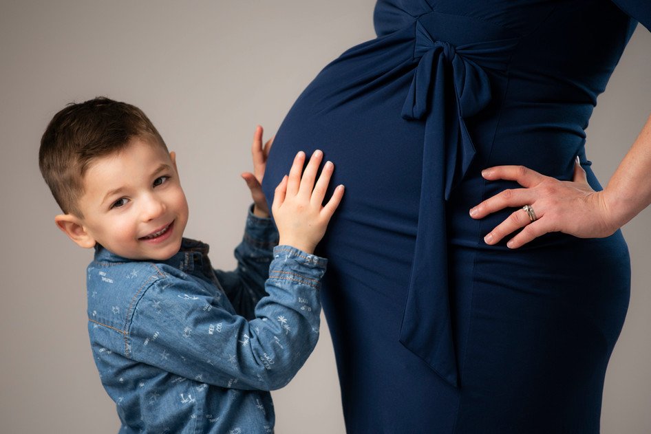 little boy hugging belly of pregnant mother