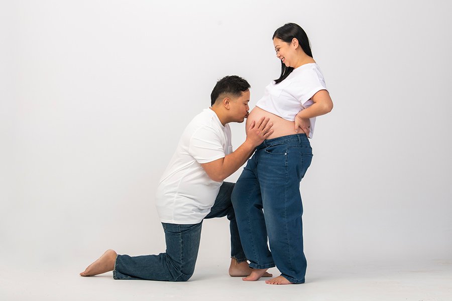 husband kissing pregnant wife's belly